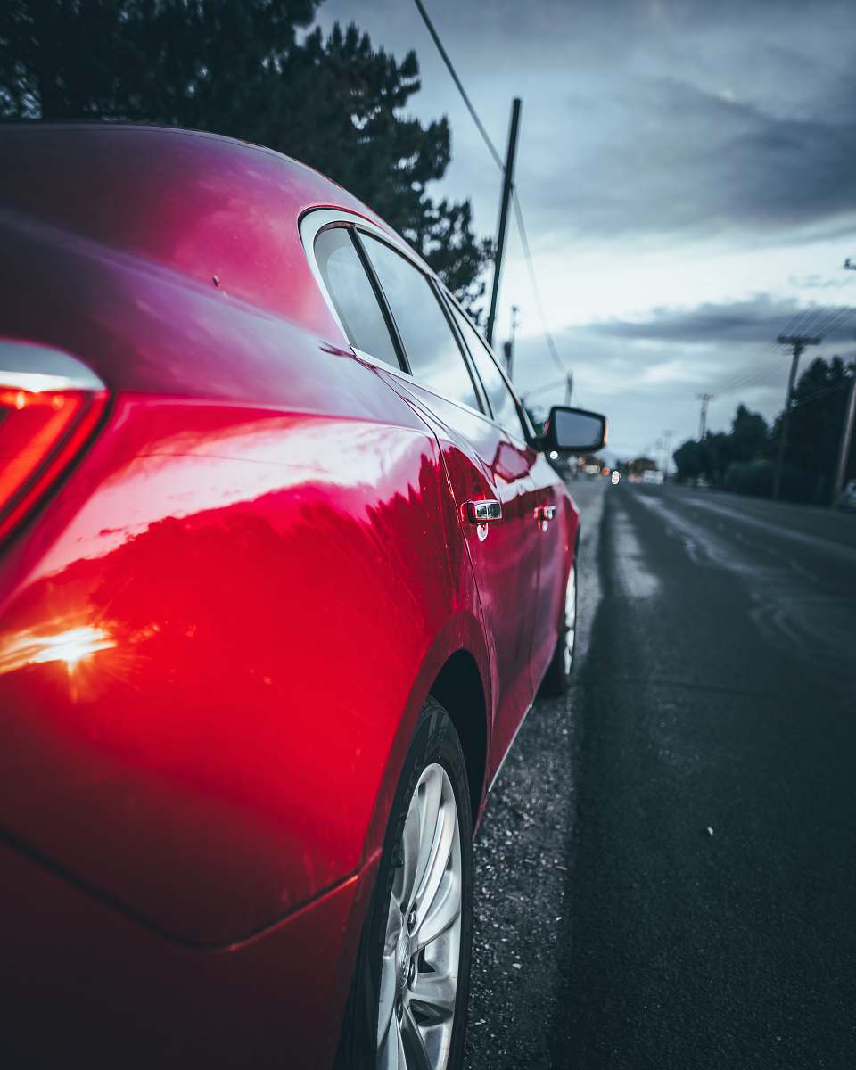 alloy wheel red sedan on road near utility pole machine
